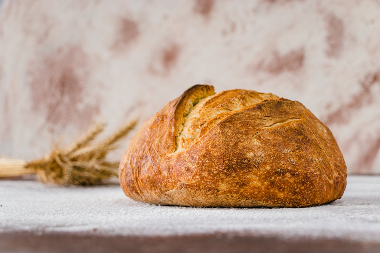 Rustic artisanal bread placed on a flour-dusted surface, showcasing crust texture in a minimalist setting.