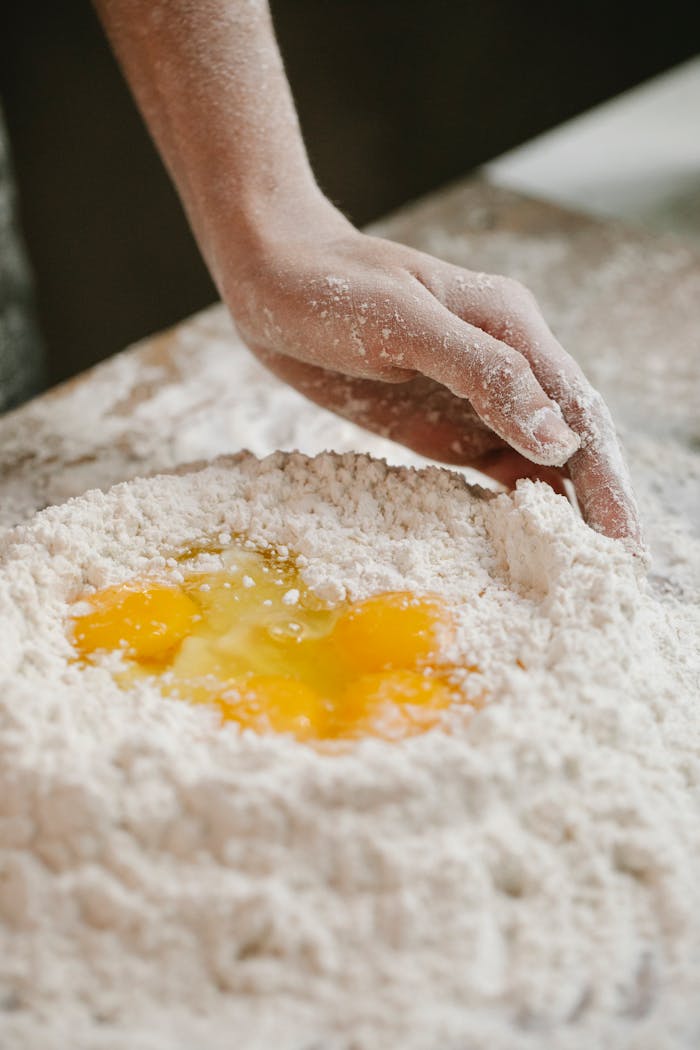 Close-up of a hand mixing eggs and flour to make dough at home. Perfect for culinary projects.